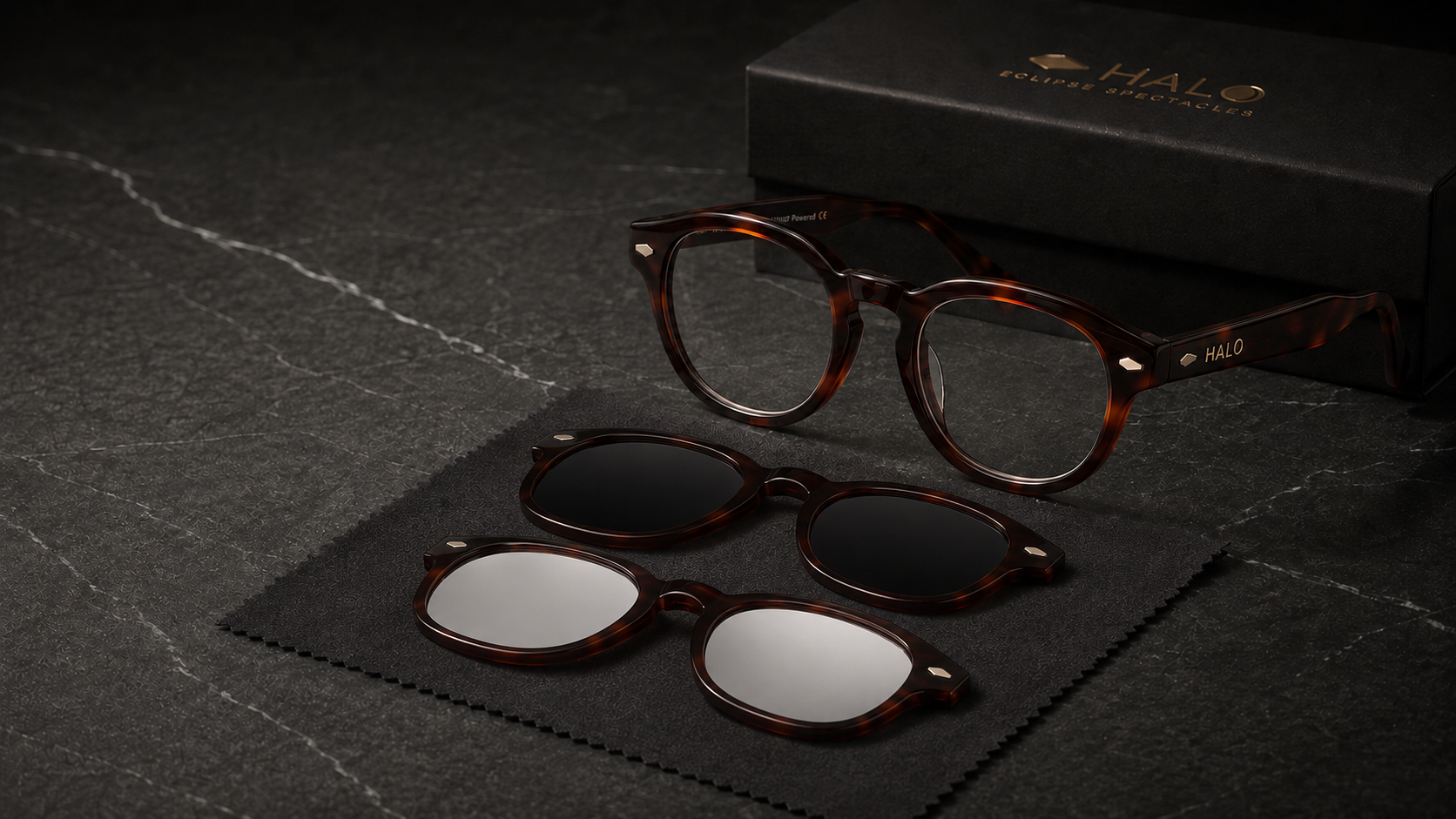 The HALO system in tortoiseshell acetate: one clear blue-light frame with two connected magnetic overlays, a dark sun front and a silver eclipse front, beside the HALO case